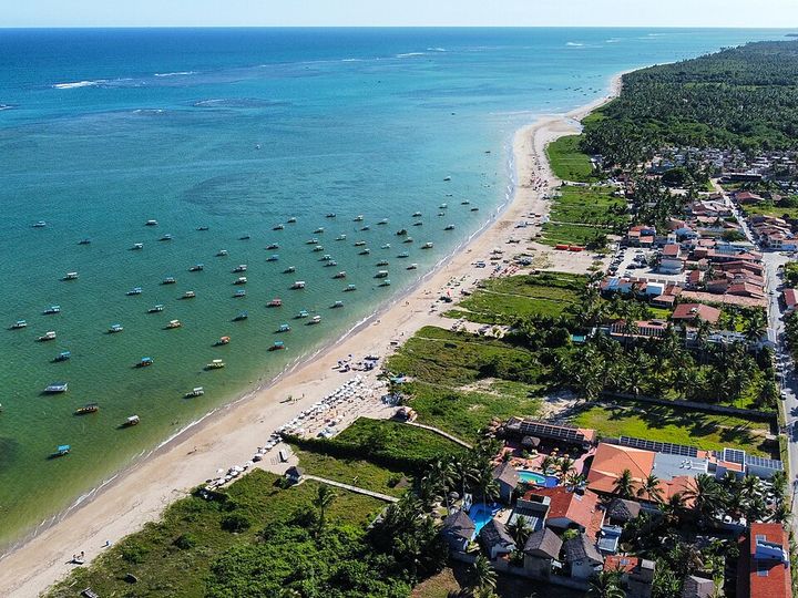 Vista aérea do mar turquesa e das jangadas em São Miguel dos Milagres